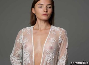 Woman in a sheer lace robe posing in a studio, with the robe partially open at the front.