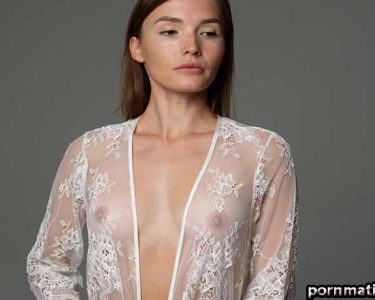 Woman in a sheer lace robe posing in a studio, with the robe partially open at the front.