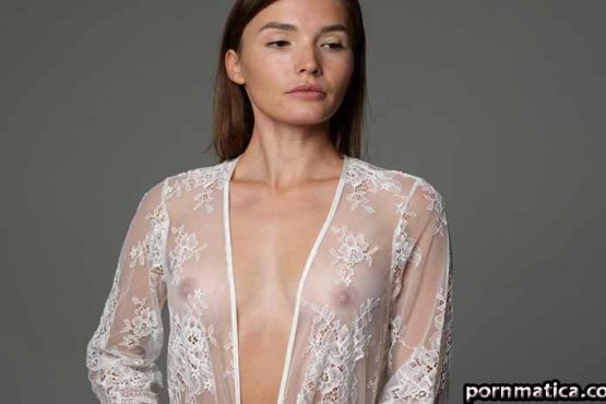 Woman in a sheer lace robe posing in a studio, with the robe partially open at the front.