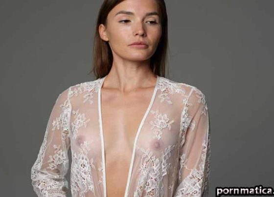 Woman in a sheer lace robe posing in a studio, with the robe partially open at the front.